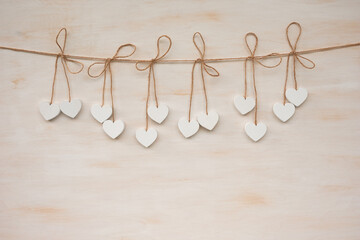A garland of several white hearts hanging against a wooden background