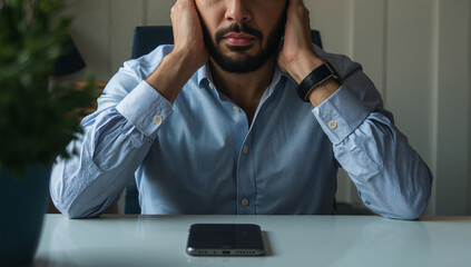 在宅ワークの机で連絡を待ち頭を抱える日本人男性