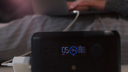 Fototapeta premium Portable power station charging a laptop while someone works remotely from a comfortable setting