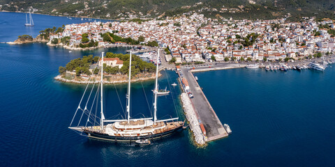 Aerial drone panoama of Skiathos Old Town and Bourtzi with Giant Three-Masted Frigate Sailing Ship Moored at Port in Greece