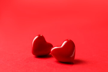 Fototapeta premium Love. Two decorative hearts on red background, closeup. Space for text