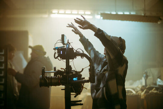 The director of photography is a woman behind a video camera on the set. A professional videographer at work on the filming of a movie, commercial or TV series. Filming process indoors, studio