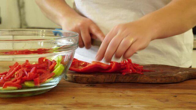 Woman cutting red pepper for salad
