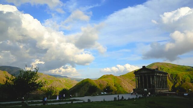 Garni Temple Armenia Mountain Landscape. Wide view of ancient Garni Temple in Kotayk Province Armenia set in green hills under blue sky ideal for tourism culture and travel ads. Static wide shot on tr