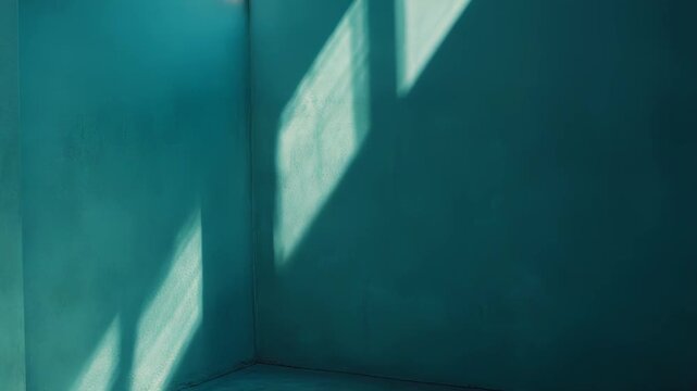 Bare turquoise walls and concrete floor featuring sharp diagonal and horizontal shadows from a window, creating a serene and contemplative abstract scene