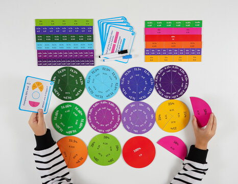 A creative flat lay showing a student solving mathematical problems using bright fraction manipulatives. Ideal for educational content, STEM learning, and school materials.