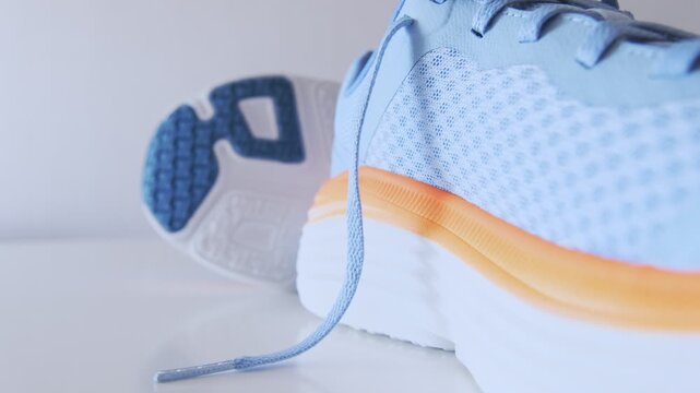 Pair of modern running shoes featuring blue mesh and orange accents on a white background