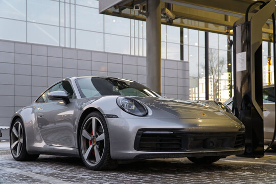Silver Porsche 911 Carrera S VIII (992), 2021 sports car parked at the city street. Grey coupe car Porsche 911 Carrera S VIII 992 on parking lot. The modern exterior Porsche 911 4S Germany sport car.