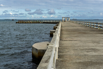 Fototapeta premium Bois des Amourettes, Mauritius - Long concrete pier stretching over calm coastal waters under a partly cloudy sky
