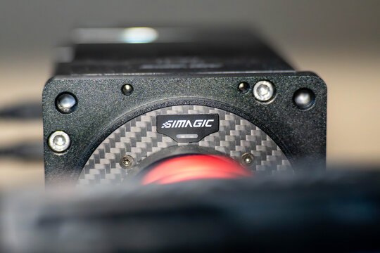 Budapest, Hungary - January 23, 2026: Professional Simagic sim racing wheel base featuring premium carbon fiber finish and red anodized quick release. High-end eSports gaming hardware.