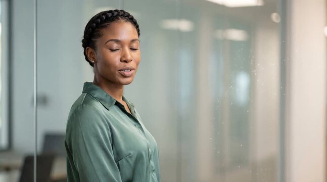 A focused woman is deep in thought, inside a modern office space. The image evokes a sense of peace and concentration.