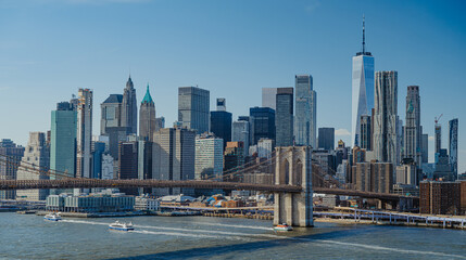 City skyline shows tall buildings and a bridge during a sunny day in New York. Tall buildings rise...