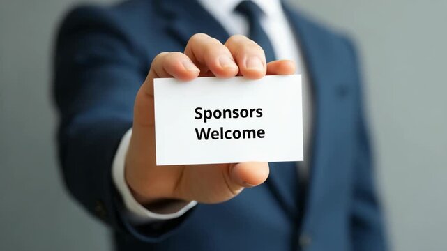 A businessman in a suit holding a card with the text 'Sponsors Welcome.' Concept photo for business partnership, sponsorship opportunities, and professional networking.