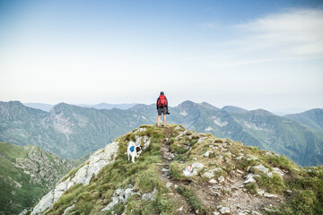 man trekking with a dog in high mountains