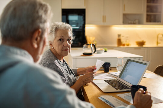 Senior couple reviewing bills on laptop in kitchen