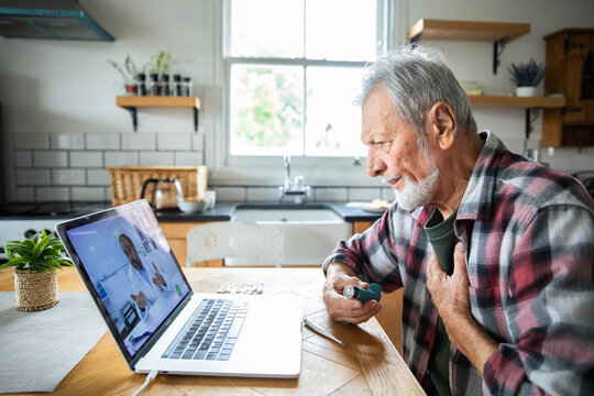 Senior man consulting doctor online at home with inhaler