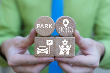 Business person holding wooden blocks with icons sees the text PARK. Concept of parks, public nature relaxation, recreation, sustainability.