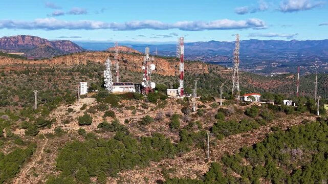 Orbiting aerial footage of a mountain telecom complex with lattice towers, microwave dishes and relay equipment, illustrating high-altitude wireless, broadcast and data transmission infrastructure