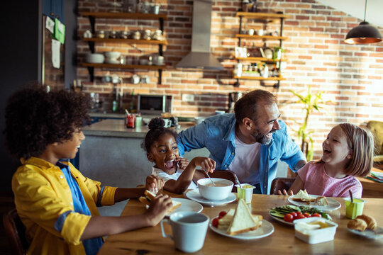 Father and children laughing at breakfast in home kitchen