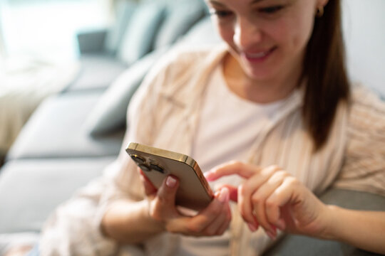 Smiling woman using smartphone on sofa at home