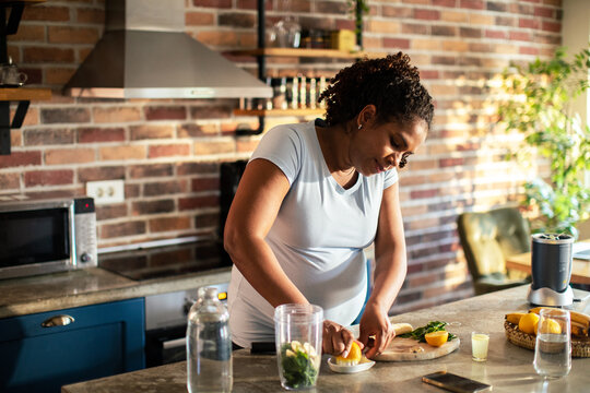 Woman juicing lemons for smoothie in sunny home kitchen