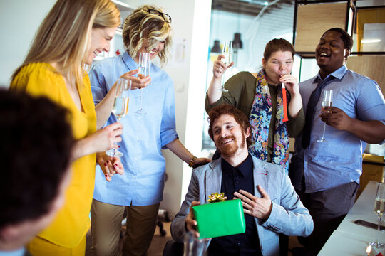 Coworkers celebrating colleague with gift at office party