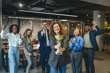 Diverse business team celebrating achievement winning golden trophy