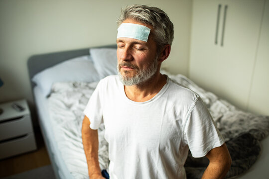Senior man with fever patch resting in bedroom at home