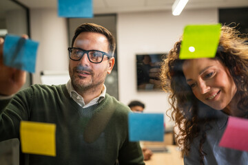 Obraz na płótnie Canvas Diverse business team collaborating planning ideas on glass wall