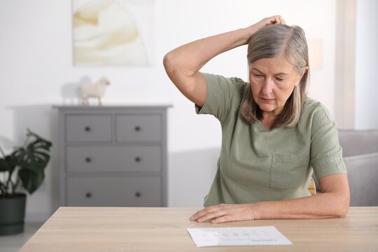 Amnesia. Senior woman trying to remember something at wooden table, space for text