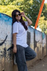 Teenage girl in urban style leaning against a wall in the park
