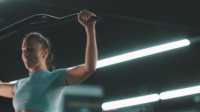 Athletic woman training back muscles on lat pulldown machine