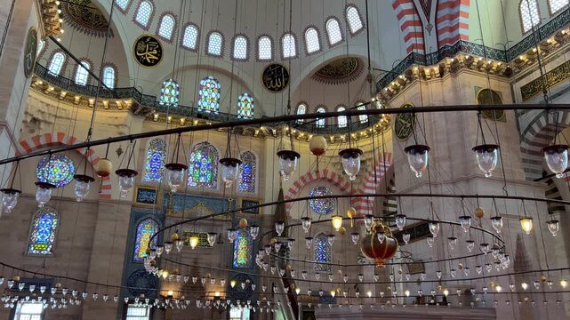Istanbul, August 9, 2024: Inside the S&uuml;leymaniye Mosque. The prayer hall is decorated with blue tiles, stained glass windows, Quranic verses, and ornaments. The floor is covered with a large carpet.4К