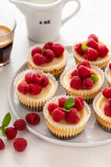 Mini cheesecakes topped with fresh raspberries on a serving plate