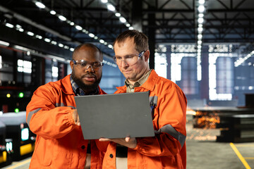 Obraz premium Engineering team managing assembly workflow with equipment, standing near steel machinery and fabrication stations for industrial development. Structured manufacturing process.
