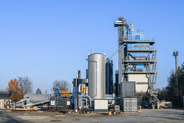 Modern Asphalt Production Plant With Industrial Silos and Machinery Under Blue Sky