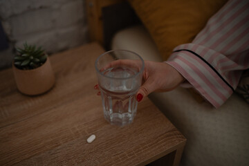 Woman in pajamas taking medication with water