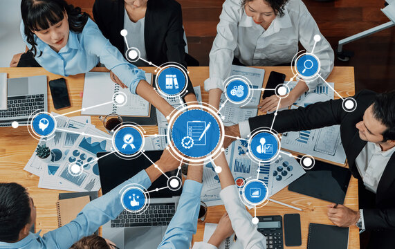 A diverse business team collaborates in a modern office setting, engaged in strategic planning. Digital icons highlight technology role in enhancing teamwork and efficiency. Amity
