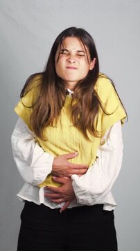 Young woman standing in a studio with a clean neutral background, showing a natural and confident expression while posing casually. Concept of modern lifestyle, self-confidence, authenticity, and huma