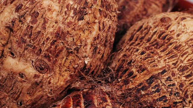 Taro vegetable tubers, Stack of raw, unpeeled tropical taro, Colocasia esculenta, on a market stall