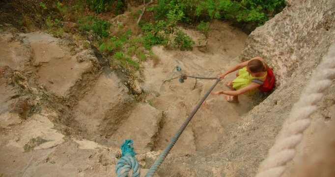 Woman climbs down the steep rocky path to reach the hidden Diamond Beach in Nusa Penida Indonesia