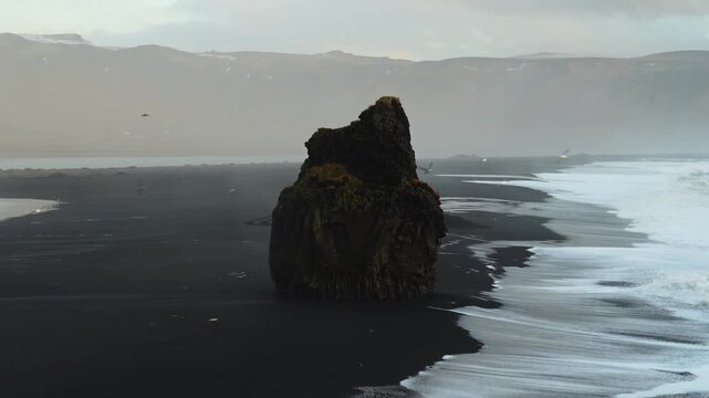 Static close-up of Reynisdrangar sea stack with seagulls and crashing waves on black sand beach, Iceland. HD 1080p.