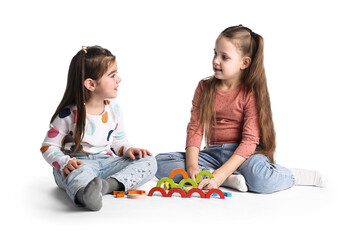 Naklejka premium Cute little girls playing with colorful wooden pieces on white background