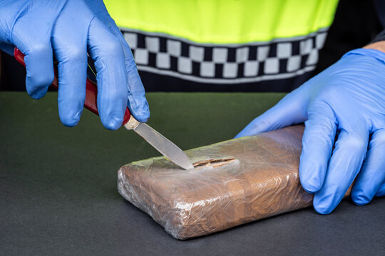Close-up of a police officer&rsquo;s hands opening a drug package.