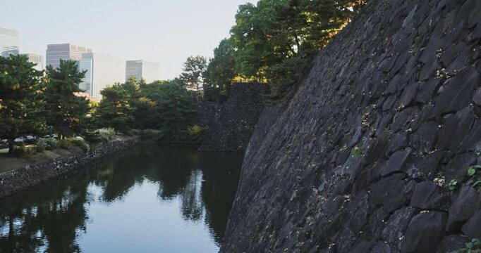 Stone wall near moat of Japanese castle at sunrise