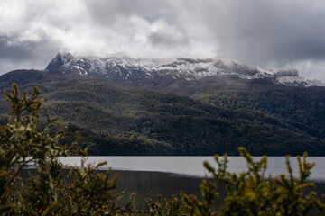 Snow-capped mountain range above a dark lake