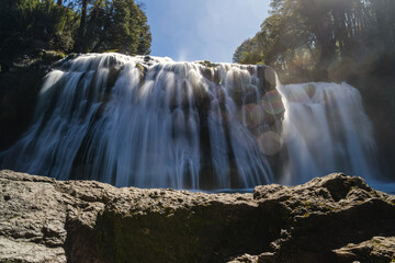 Low angle long exposure of a wide forest waterfall