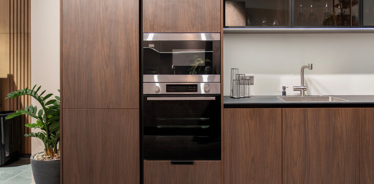 Built-in oven and microwave in modern dark wood kitchen
