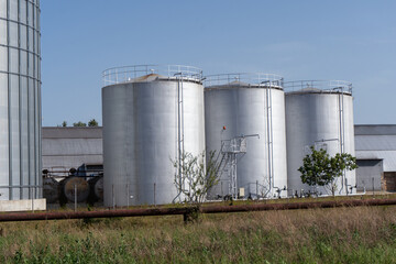 Storage Silos Stand in a Field Near a Building Under Clear Sky During Daylight Hours © Роман Булатов