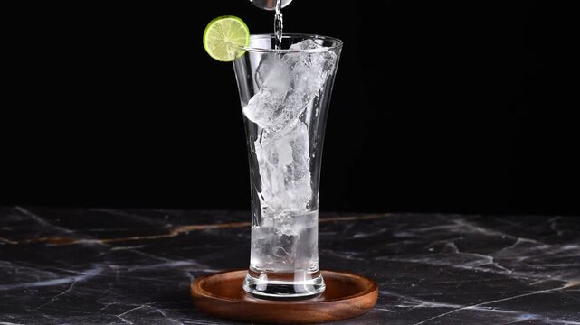 Cuba libre drink, Close-up of hands pouring rum into a glass with ice cubes to prepare a rum and coke cocktail, slow motion
